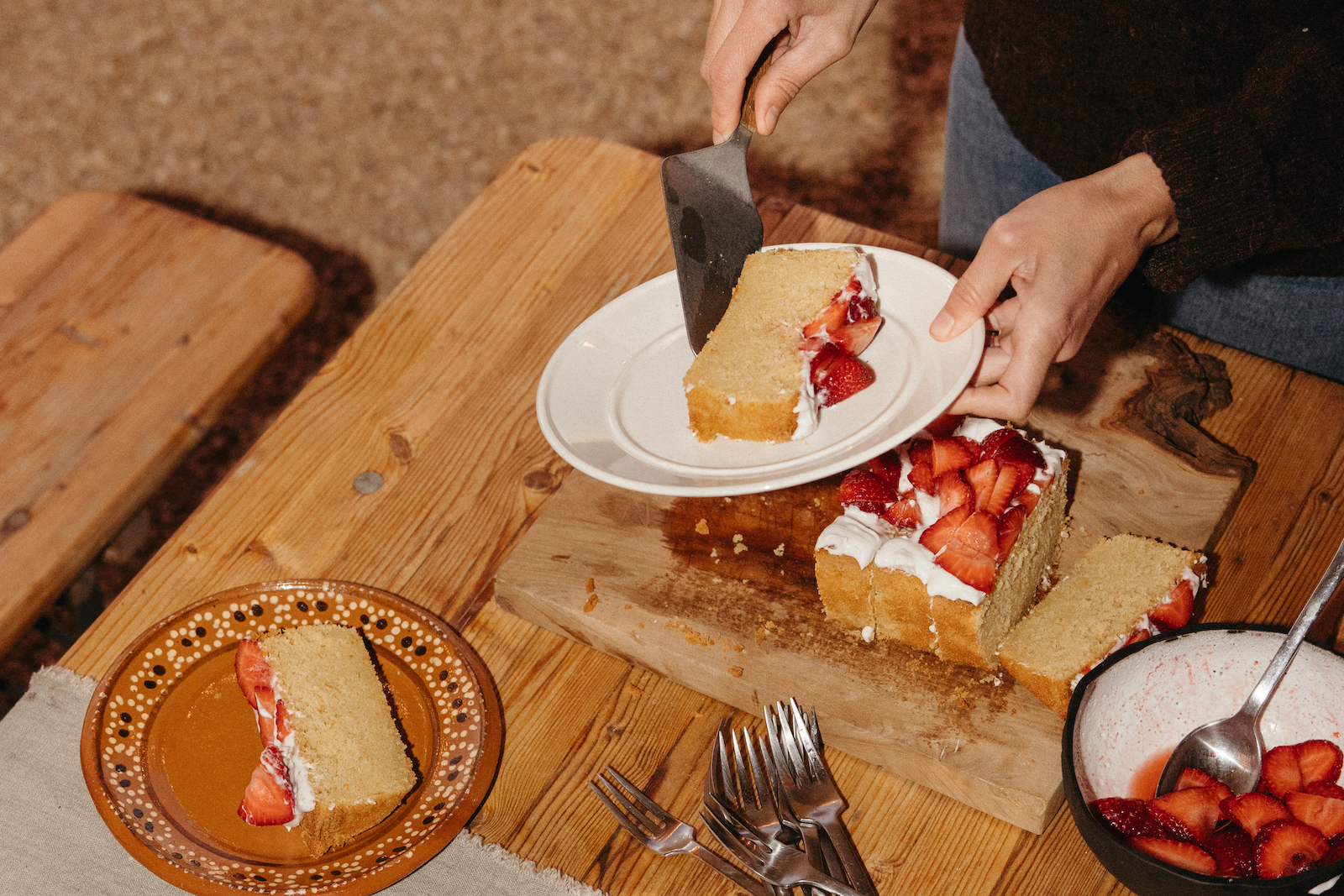 Serving slices of gluten-free citrus cake with strawberries.